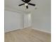 Neutral bedroom with light wood floors and ceiling fan leads into closet and next room at 7815 Shadow Run Dr, Largo, FL 33773