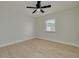 Bright bedroom featuring light wood floors, a ceiling fan, and a window with lush green trees outside at 7815 Shadow Run Dr, Largo, FL 33773