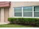 Close exterior of the condo building showing unit 4, a window, and manicured shrubbery at 10033 64Th N Ave # 4, St Petersburg, FL 33708