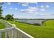Serene backyard view featuring lush greenery, a calm lake, and houses in the distance at 1012 Seminole Sky Dr, Ruskin, FL 33570