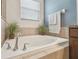 The primary bathroom features a soaking tub with tile surround, a faucet, and a window with blinds at 1012 Seminole Sky Dr, Ruskin, FL 33570