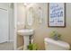 Well-lit half-bath with a pedestal sink, toilet, and decorative wall art at 1012 Seminole Sky Dr, Ruskin, FL 33570
