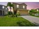 Charming two-story home featuring a well-manicured lawn, palm tree, and two-car garage at sunset at 1012 Seminole Sky Dr, Ruskin, FL 33570
