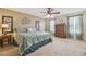 This primary bedroom features a ceiling fan, neutral walls and carpet, and a large window with decorative curtains at 1012 Seminole Sky Dr, Ruskin, FL 33570