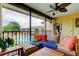 Cozy screened balcony featuring wicker seating, wooden tables, ceiling fan, and scenic pool views at 12261 Sailwinds Dr # 203, Largo, FL 33773