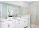 A bright bathroom features double sinks, vanity, mirror and a glass door shower at 12586 Somatic Ct, Venice, FL 34293