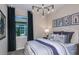 This bedroom features a modern light fixture, neutral walls, and a window with black curtains at 13740 Rocky Pine Pl, Spring Hill, FL 34610