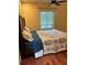Cozy bedroom features a ceiling fan, window with blinds, and a comfortable bed with floral bedding at 1400 Pine Glen Ln # D2, Tarpon Springs, FL 34688