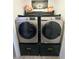 Efficient laundry room with front-loading machines, storage cabinets, and stylish decor at 14509 Thornfield Ct, Tampa, FL 33624