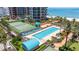 A resort-style pool area with tennis courts, lush landscaping, and ocean views at 1520 Gulf Blvd # 1502, Clearwater Beach, FL 33767