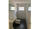 Bright bathroom with a stand alone sink, dark floor, tiled walls and a window for natural light at 1875 Harmony Dr, Clearwater, FL 33756