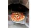 Pizza is placed inside the pizza oven, ready to be cooked to perfection at 1875 Harmony Dr, Clearwater, FL 33756