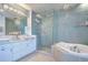 Elegant bathroom featuring a soaking tub, a glass shower, and dual vessel sinks at 288 Beach Ne Dr # 12C, St Petersburg, FL 33701