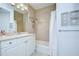 Well-lit bathroom featuring a single sink vanity, tiled shower and tub combo, with decorative seashell art at 288 Beach Ne Dr # 12C, St Petersburg, FL 33701