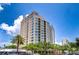Beautiful high-rise condominium building featuring a light tan exterior, curved balconies, and verdant, mature landscaping at 288 Beach Ne Dr # 12C, St Petersburg, FL 33701