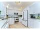 Bright white kitchen with stainless steel appliances, custom cabinets, tile backsplash, and light wood floors at 288 Beach Ne Dr # 12C, St Petersburg, FL 33701