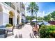 Charming outdoor seating area with tables, chairs, umbrellas, brick pavers, and lush landscaping at 288 Beach Ne Dr # 12C, St Petersburg, FL 33701
