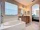 Spacious bathroom with soaking tub, dual vanity with stone countertops, and open view into the main bedroom at 3409 61St E Ter, Ellenton, FL 34222