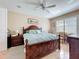Spacious main bedroom with wood floors, a ceiling fan, plantation shutters, and a large decorative wooden bed frame at 3409 61St E Ter, Ellenton, FL 34222