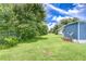 View of backyard featuring green lawn and partial view of blue home exterior at 35014 Carl Ave, Zephyrhills, FL 33541