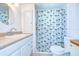 Bright bathroom features a vanity with a round mirror and a shower with a decorative palm tree curtain at 35014 Carl Ave, Zephyrhills, FL 33541