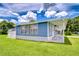 Charming blue home with bright white trim and a well-manicured lawn under a partly cloudy sky at 35014 Carl Ave, Zephyrhills, FL 33541