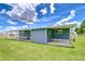 Exterior view of blue home with a covered patio, spacious yard, and satellite dish at 35014 Carl Ave, Zephyrhills, FL 33541