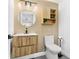 Modern bathroom featuring a hardwood cabinet, round mirror and decorative plants at 380 Colony Point S Rd, St Petersburg, FL 33705