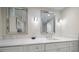 Bathroom vanity with a marble countertop, crystal knobs, white cabinets, and framed mirrors with sconces at 4 Belleview Blvd # 305, Belleair, FL 33756