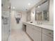 Bright bathroom featuring double vanity, white cabinets, marble countertops, and glass shower with neutral tile at 4 Belleview Blvd # 305, Belleair, FL 33756