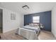 Cozy bedroom featuring wood-look floors, a navy accent wall and neutral colored bed linens at 4020 N Falkenburg Rd, Tampa, FL 33610
