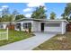 Inviting home exterior featuring a concrete driveway, landscaped lawn, and a charming white and gray facade at 4020 N Falkenburg Rd, Tampa, FL 33610