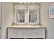 Well-lit bathroom with dual sinks, granite countertop, white cabinets, and decorative mirrors at 4415 Muirfiled Dr, Bradenton, FL 34210