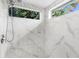 Bright bathroom features white marble tiled walls, shower, and sunlit windows offering green leafy views at 4511 Preston Woods Dr, Valrico, FL 33596