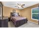 Cozy bedroom with tan walls, a window with blinds, a ceiling fan, and a dark wood bed frame at 4511 Preston Woods Dr, Valrico, FL 33596
