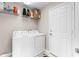 Bright laundry room features a washer, dryer, storage shelf, and a white door at 4511 Preston Woods Dr, Valrico, FL 33596
