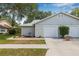Charming single-story home with light gray siding and a single-car garage, featuring an inviting driveway at 4532 Cedarwood Village Dr, Tampa, FL 33624