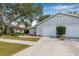Charming single-story home with light gray siding, complemented by a well-maintained lawn and mature trees at 4532 Cedarwood Village Dr, Tampa, FL 33624