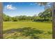Large grassy field surrounded by forest and a stone wall at 4532 Cedarwood Village Dr, Tampa, FL 33624