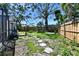 Landscaped backyard with stepping stones, wooden fence, and mature trees, offering privacy and natural beauty at 4735 Baywood Point S Dr, Gulfport, FL 33711