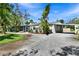 Exterior view of a well-maintained home with a lush lawn, mature trees, and a convenient carport at 4735 Baywood Point S Dr, Gulfport, FL 33711