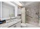 Bathroom with gray granite countertop, white cabinetry, and bathtub with white and gray marble patterned shower at 6209 S Harold Ave, Tampa, FL 33616