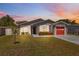 Charming single-story home featuring a red garage door, stone accents, and well-maintained landscaping at 6209 S Harold Ave, Tampa, FL 33616