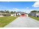 Single-story home featuring a long driveway and colorful flowers by the entryway at 6209 S Harold Ave, Tampa, FL 33616