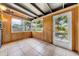 Bright sunroom with wood paneling, tile floors, large windows, and a glass door at 762 77Th N Ave, St Petersburg, FL 33702