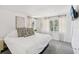 Bedroom featuring a king-size bed with a white comforter and decorative pillows, flanked by windows with light filtering curtains at 8500 144Th Ln, Seminole, FL 33776