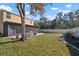 Large backyard with healthy green grass, mature trees, and an enclosed patio at 8607 Tidal Breeze Dr, Riverview, FL 33569