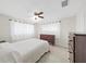 Cozy bedroom with a ceiling fan, two dressers, and two windows with white curtains at 9413 Forest Hills Dr, Tampa, FL 33612