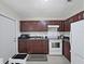 Galley style kitchen featuring dark wood cabinets, white appliances, and tile flooring at 9413 Forest Hills Dr, Tampa, FL 33612