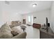 Bright living room with neutral tile floors, a sofa, entertainment center, and access to the front door at 9413 Forest Hills Dr, Tampa, FL 33612